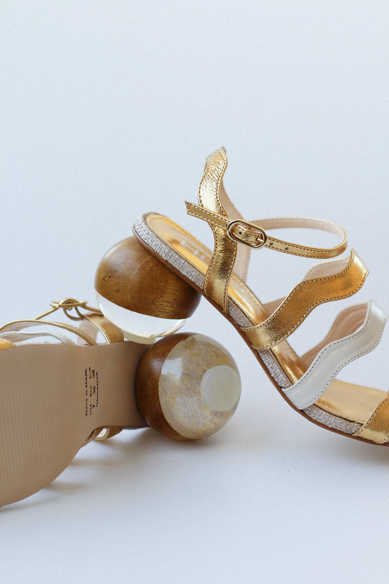 Gaspea sandal in gold and off-white with acrylic sphere heel and chestnut wood.